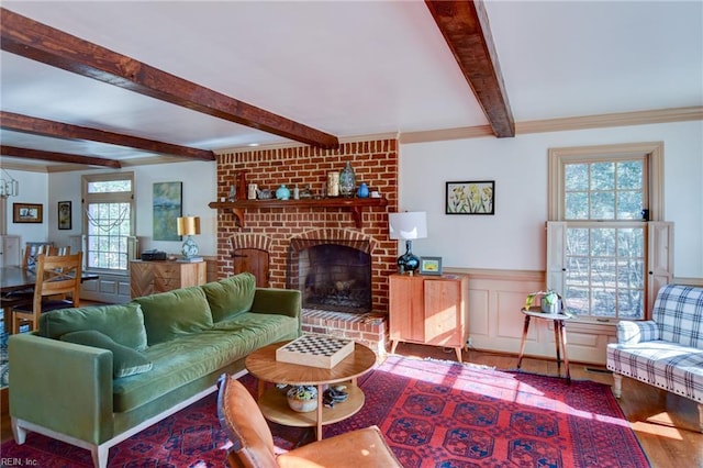 living room featuring beamed ceiling, hardwood / wood-style flooring, a brick fireplace, and plenty of natural light