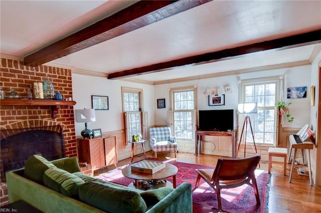 living room featuring a wealth of natural light, crown molding, wood-type flooring, and a brick fireplace