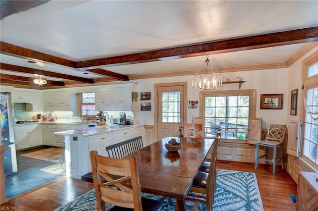 dining room with light wood-type flooring, crown molding, and a notable chandelier