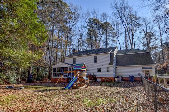 rear view of house featuring a sunroom, central AC unit, and a playground