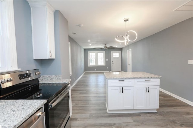 kitchen featuring light stone countertops, ceiling fan with notable chandelier, stainless steel electric stove, decorative light fixtures, and white cabinets