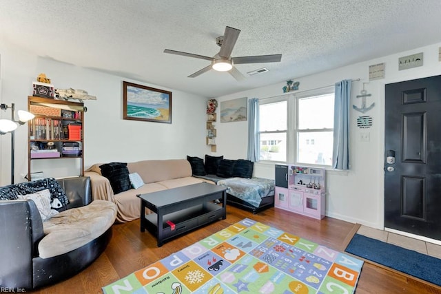 living room featuring ceiling fan, dark hardwood / wood-style floors, and a textured ceiling