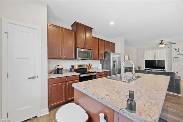 kitchen with appliances with stainless steel finishes, ceiling fan, dark wood-type flooring, sink, and a center island with sink