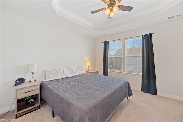 carpeted bedroom with ceiling fan and a tray ceiling