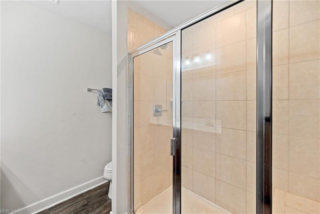 bathroom featuring hardwood / wood-style floors, toilet, and a shower with shower door