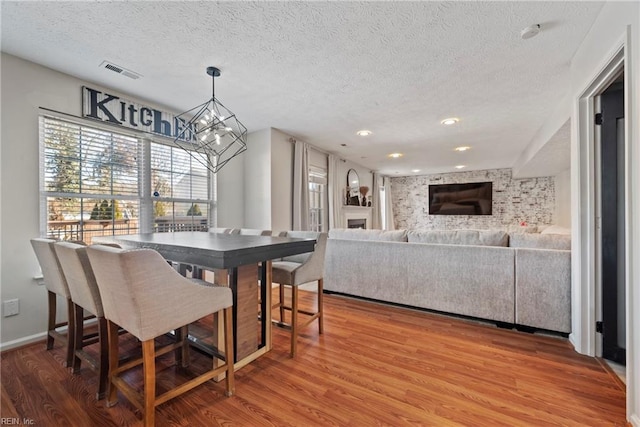 dining space featuring a notable chandelier, wood-type flooring, and a textured ceiling