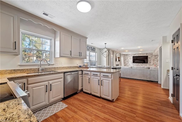 kitchen with dishwasher, sink, light hardwood / wood-style flooring, kitchen peninsula, and pendant lighting