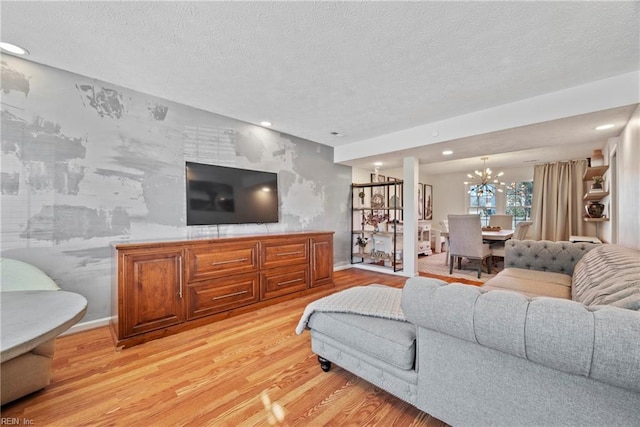 living room with an inviting chandelier, a textured ceiling, and light wood-type flooring