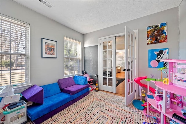 recreation room with french doors, a textured ceiling, and a healthy amount of sunlight