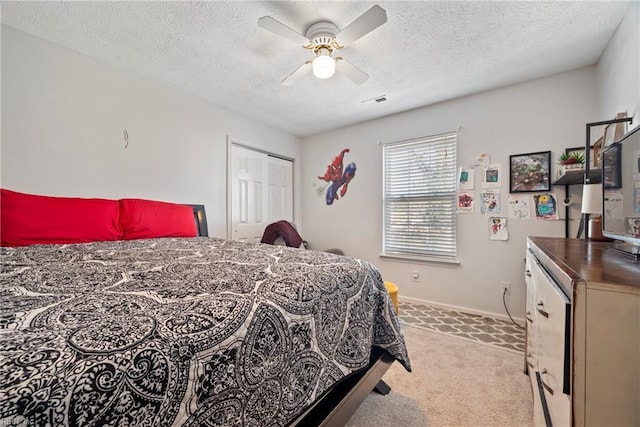 carpeted bedroom featuring ceiling fan, a textured ceiling, and a closet