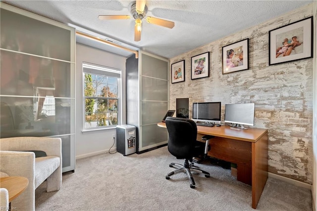 carpeted office space featuring ceiling fan and a textured ceiling