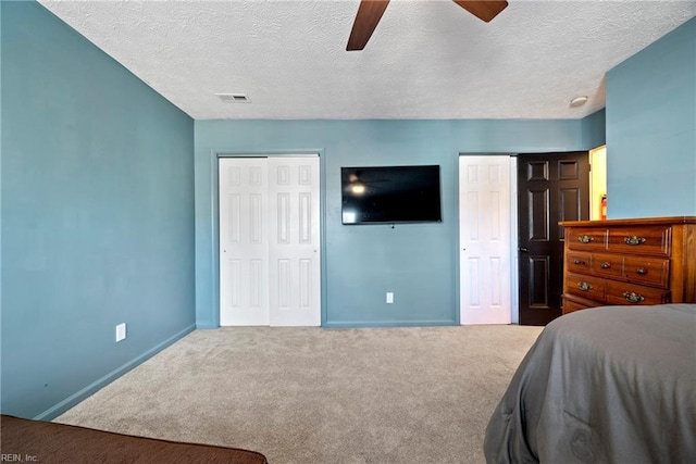 carpeted bedroom with ceiling fan and a textured ceiling