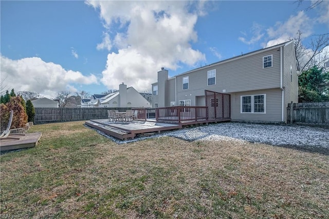 back of property with a wooden deck and a lawn