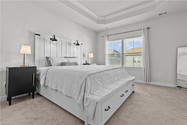 bedroom with a raised ceiling and light carpet