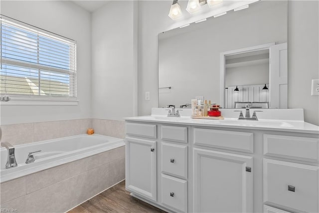 bathroom featuring vanity, wood-type flooring, and tiled bath