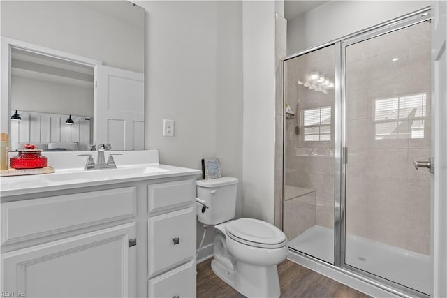 bathroom with hardwood / wood-style floors, vanity, toilet, and a shower with door