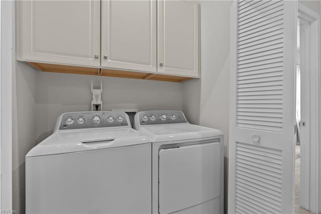 clothes washing area with cabinets and washer and dryer