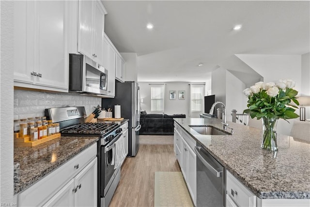 kitchen with tasteful backsplash, stainless steel appliances, sink, a center island with sink, and white cabinets