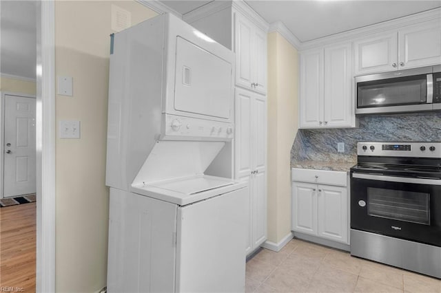 laundry room with light tile patterned floors, stacked washer and dryer, and crown molding