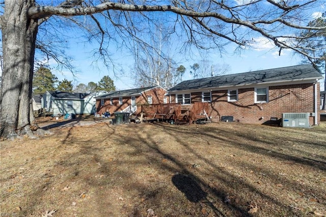 rear view of house with central AC unit, a deck, and a lawn