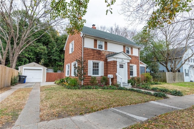 colonial-style house with a front yard, an outdoor structure, and a garage