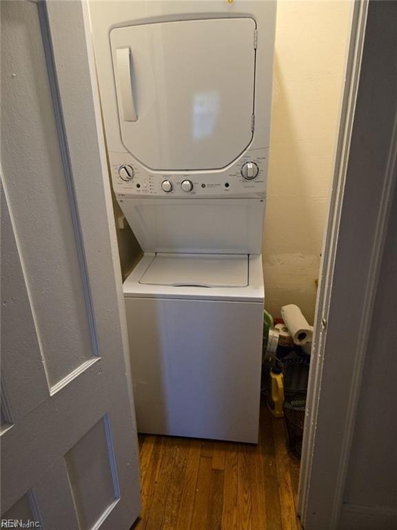 washroom with dark hardwood / wood-style flooring and stacked washer and clothes dryer