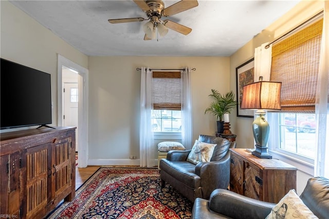 living room with light hardwood / wood-style flooring, ceiling fan, and a healthy amount of sunlight