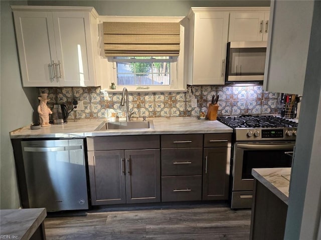 kitchen with tasteful backsplash, white cabinetry, sink, and stainless steel appliances