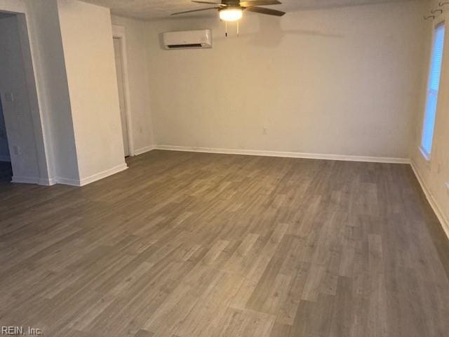 spare room with dark hardwood / wood-style flooring, an AC wall unit, and ceiling fan