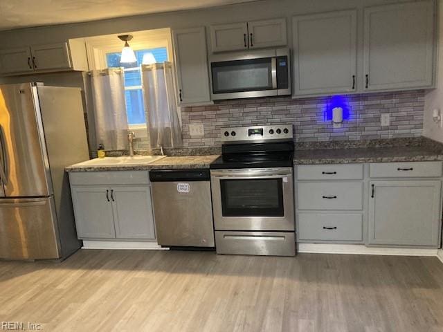 kitchen featuring decorative backsplash, stainless steel appliances, light hardwood / wood-style flooring, and sink