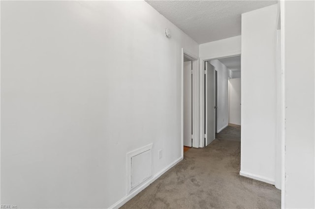 corridor featuring a textured ceiling and light colored carpet