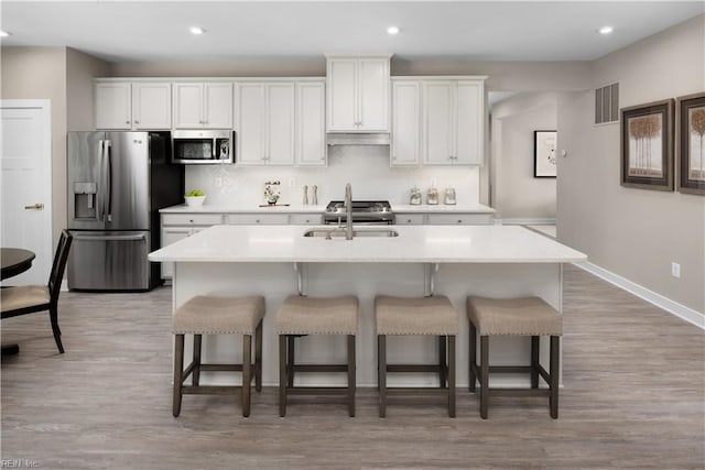 kitchen with white cabinetry, a center island with sink, sink, and appliances with stainless steel finishes