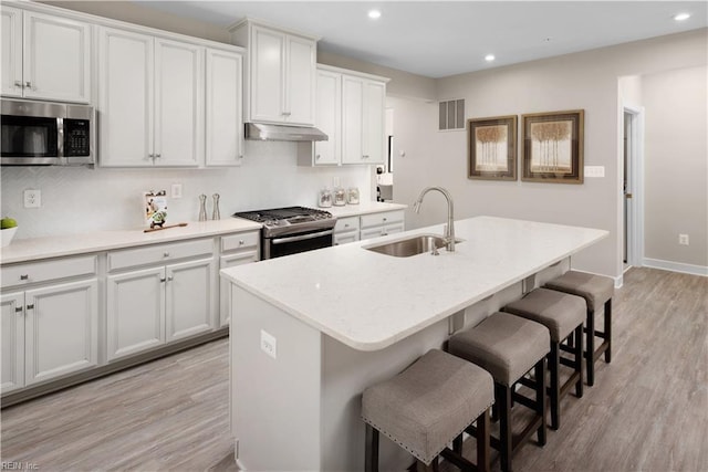 kitchen featuring white cabinets, sink, a kitchen island with sink, and appliances with stainless steel finishes