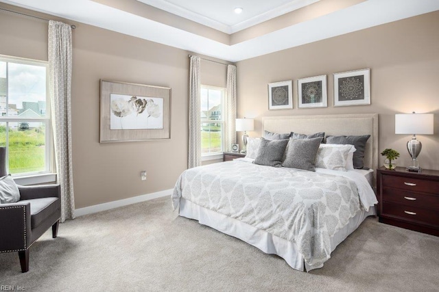 carpeted bedroom with a raised ceiling, ornamental molding, and multiple windows