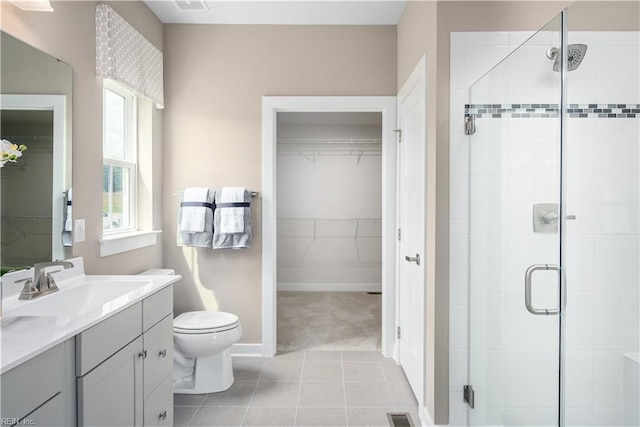 bathroom featuring tile patterned flooring, vanity, toilet, and walk in shower