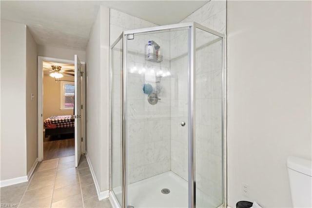 bathroom featuring tile patterned flooring, ceiling fan, toilet, and a shower with door