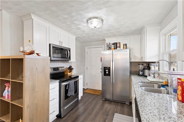 kitchen featuring light stone countertops, stainless steel appliances, sink, dark hardwood / wood-style floors, and white cabinetry