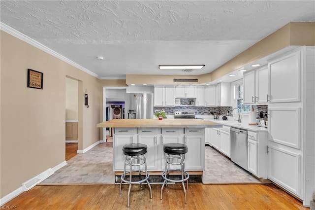 kitchen featuring white cabinetry, a center island, stainless steel appliances, light hardwood / wood-style flooring, and a kitchen bar