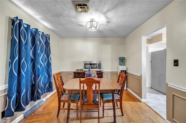 dining space featuring a textured ceiling and light hardwood / wood-style flooring