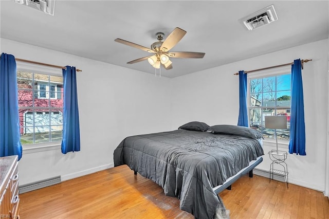 bedroom featuring ceiling fan, a baseboard radiator, and hardwood / wood-style flooring