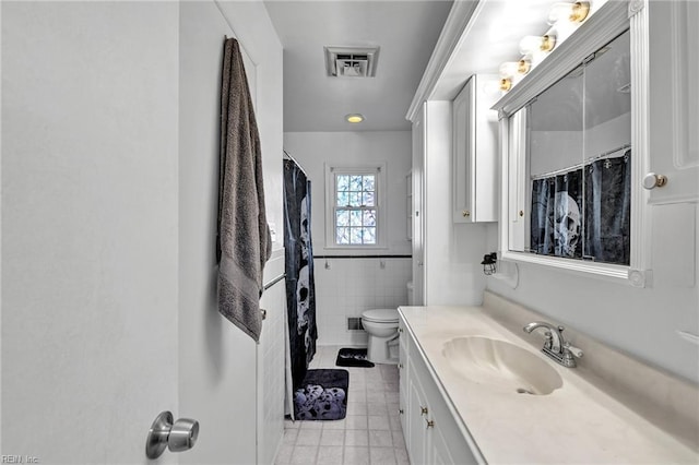 bathroom with vanity, toilet, and tile walls