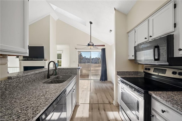 kitchen with dark stone counters, sink, white cabinets, and stainless steel appliances