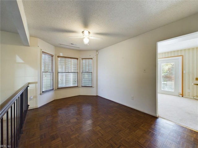 spare room featuring dark parquet flooring, ceiling fan, and a textured ceiling