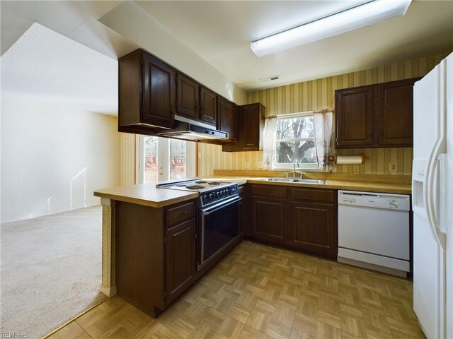 kitchen featuring kitchen peninsula, white appliances, light colored carpet, exhaust hood, and sink