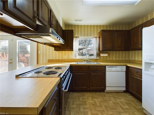 kitchen with white appliances, french doors, sink, kitchen peninsula, and light parquet flooring