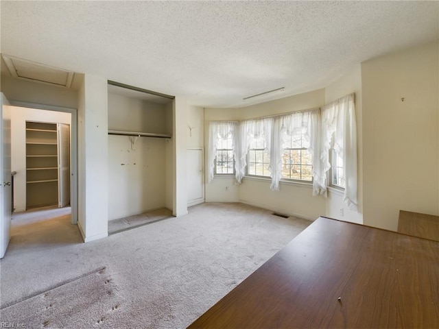 unfurnished bedroom with light colored carpet and a textured ceiling