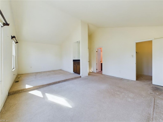 unfurnished room featuring light carpet and high vaulted ceiling