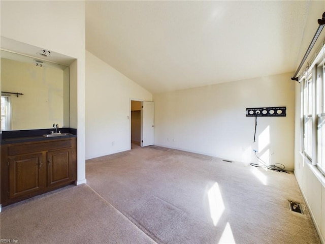 unfurnished living room with sink, light carpet, and vaulted ceiling