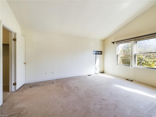 unfurnished room with light colored carpet and vaulted ceiling