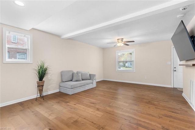 sitting room featuring ceiling fan, beam ceiling, and wood-type flooring